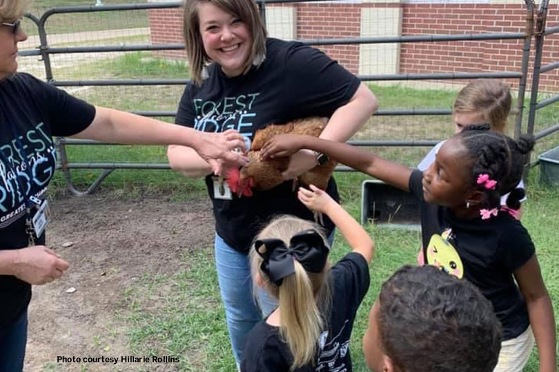 young students touch a chicken that a teacher is holding. they purchased the chickens with grants from Farm Bureau.