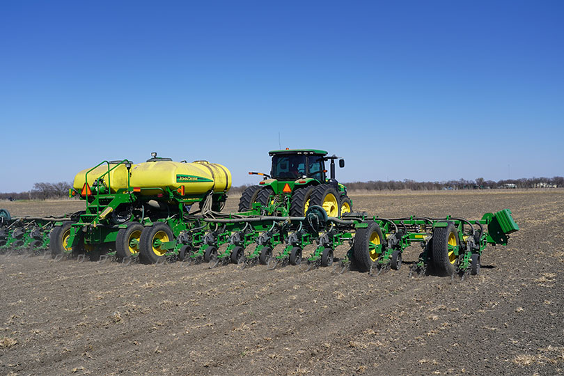 John Deere tractor and planter in field under blue sky